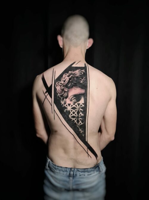 Tatouage artistique dans le dos d’un homme, portrait classique en noir et gris avec motifs géométriques et lignes graphiques