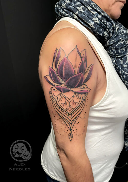Tatouage fleur de lotus dans des tons prune et violet sur le haut du bras, réalisé par Alex Needles à Boulogne-sur-Mer