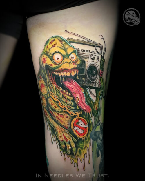 Tatouage couleur Slimer SOS Fantômes cuisse – The Needles Factory Boulogne-sur-Mer Tatouage couleur Slimer SOS Fantômes avec radio vintage sur la cuisse, réalisé par The Needles Factory, tatoueur à Boulogne-sur-Mer dans le Pas-de-Calais.