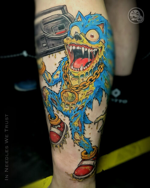 Tatouage couleur Sonic en mode zombie avec Mega Drive portée comme un ghetto blaster, sur mollet à Boulogne-sur-Mer (62).
