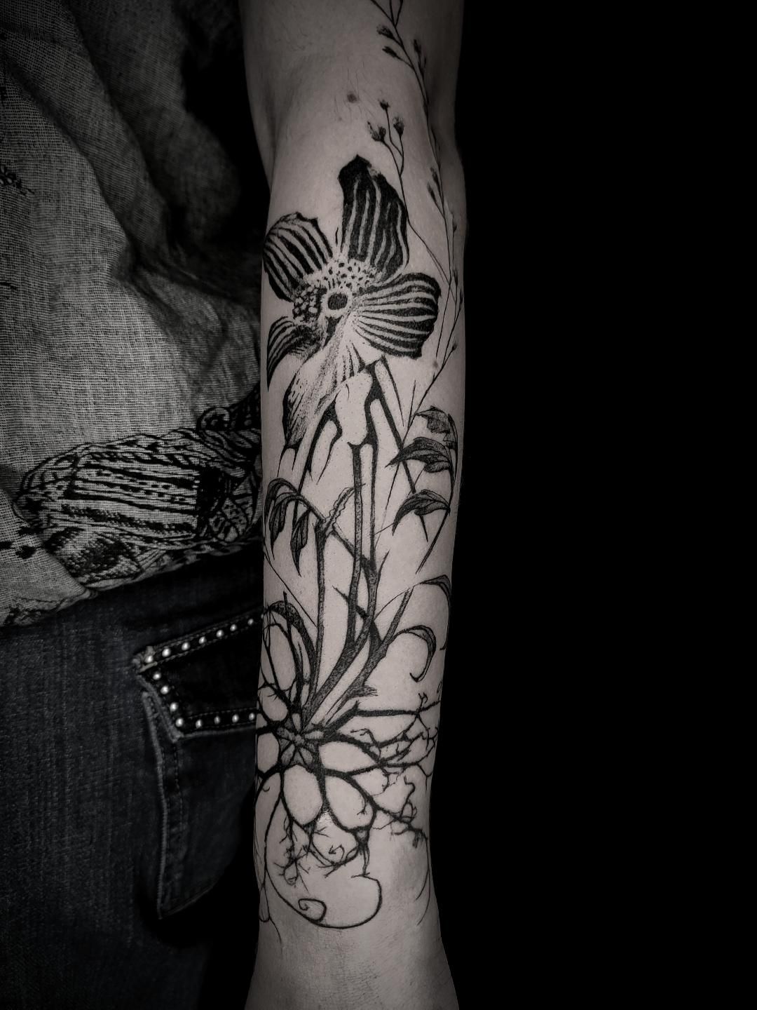Tatouage floral graphique en noir sur l’avant-bras