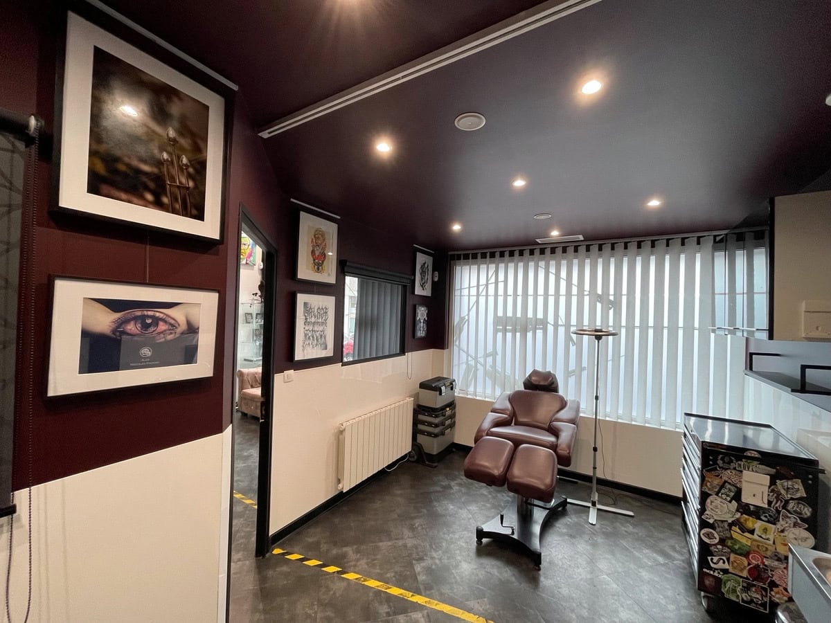 Salle du studio avec un fauteuil de travail, des murs bordeaux et crème et une grande fenêtre.